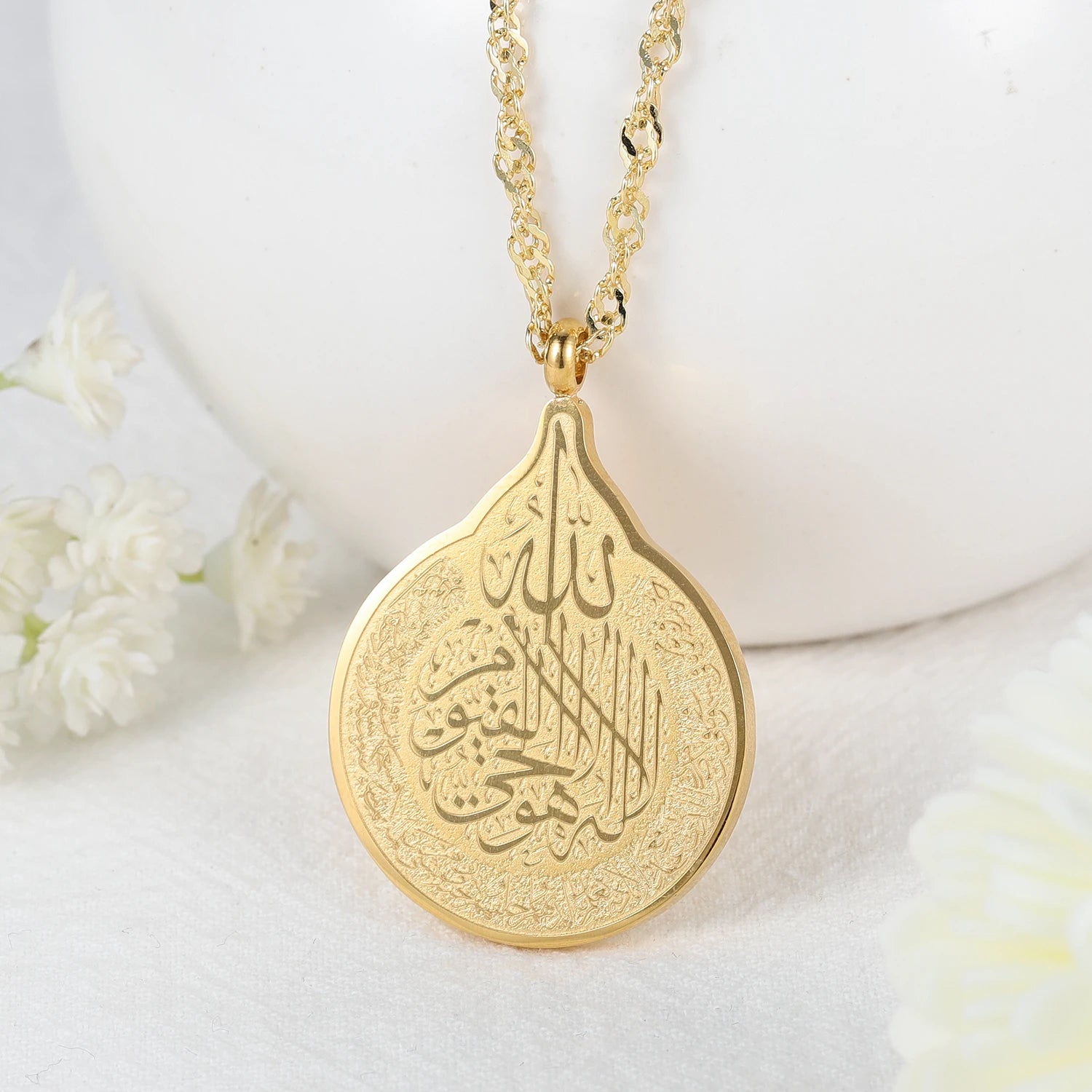 Gold necklace with a teardrop-shaped pendant on a white background