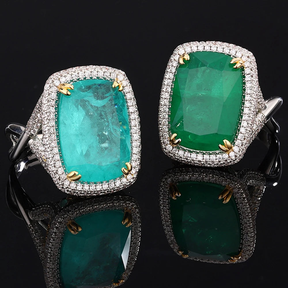 Pair of earrings with green gemstones and diamond-like stones on a black background