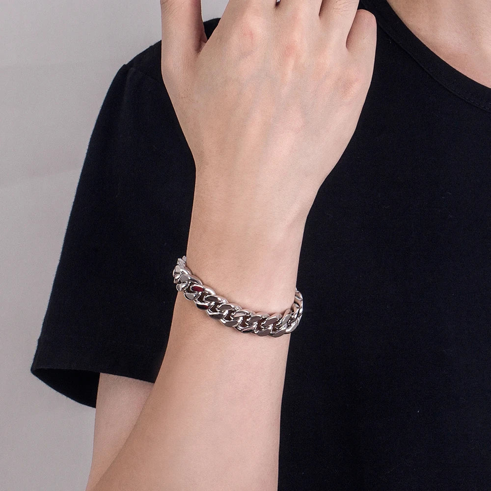 Person wearing a silver chain bracelet on a plain background