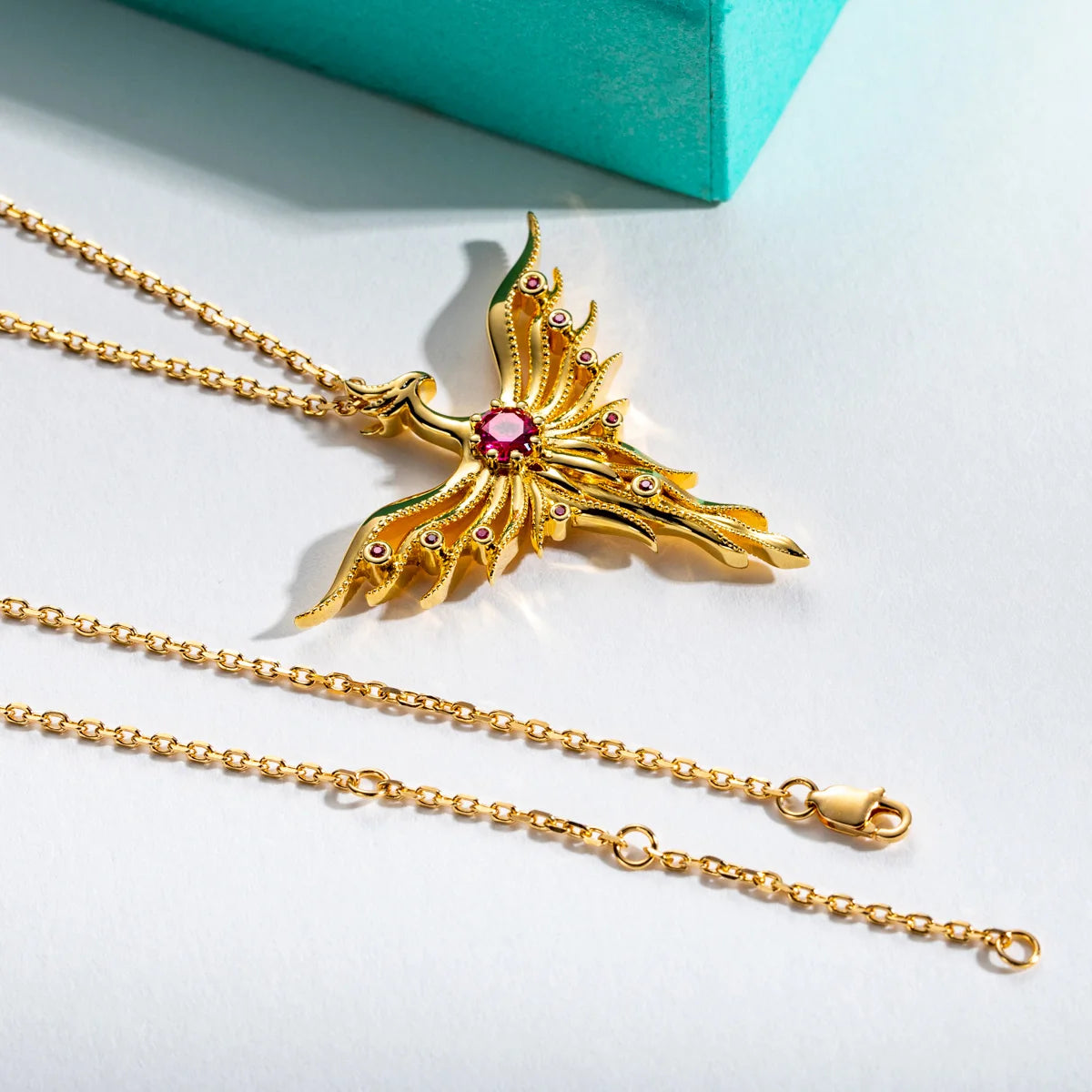 Gold necklace with a decorative pendant on a light gray background