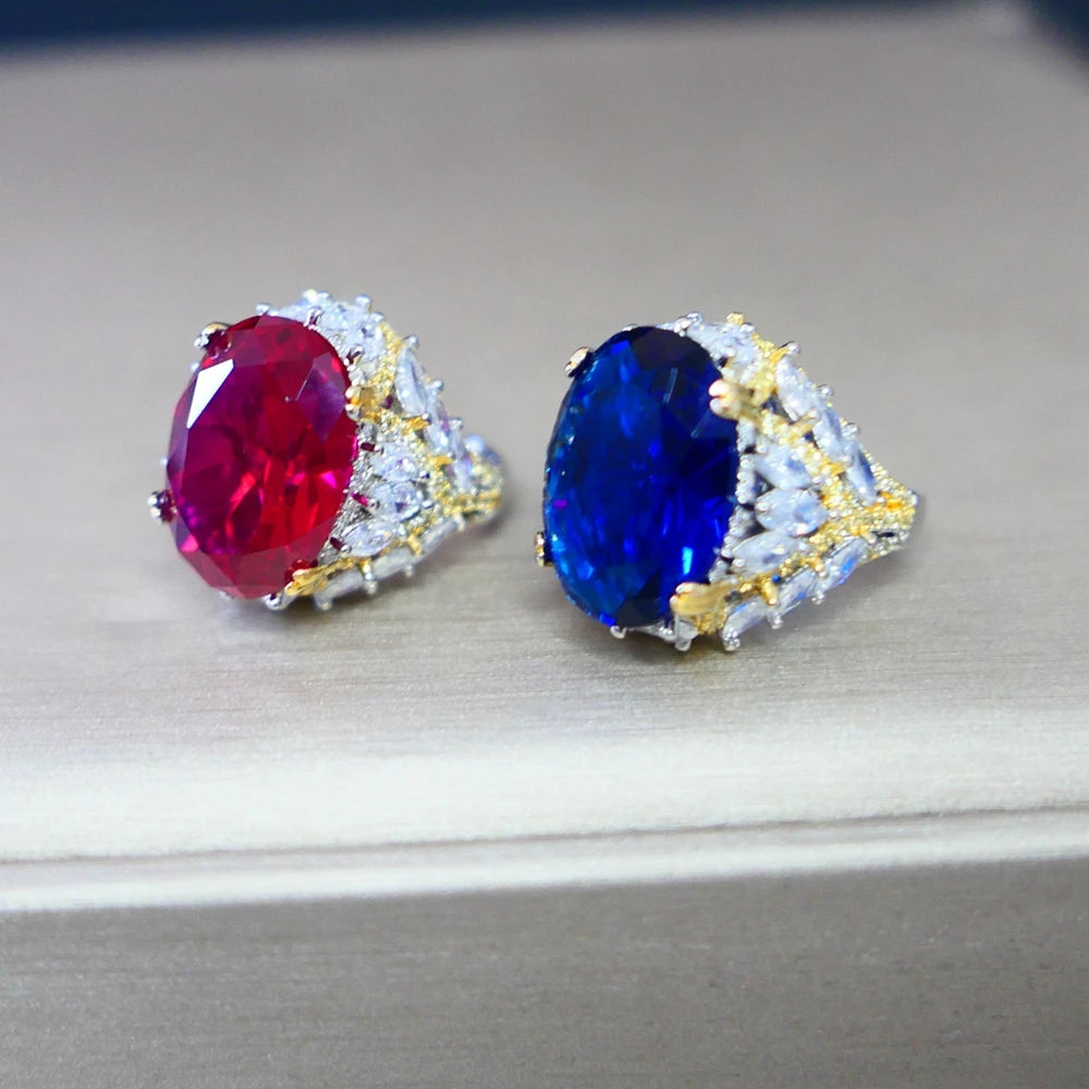 Pair of rings with red and blue gemstones on a light gray background
