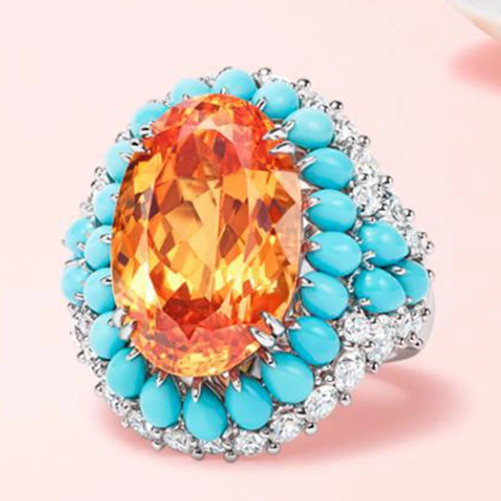 Ring with orange gemstone and turquoise stones on a pink background