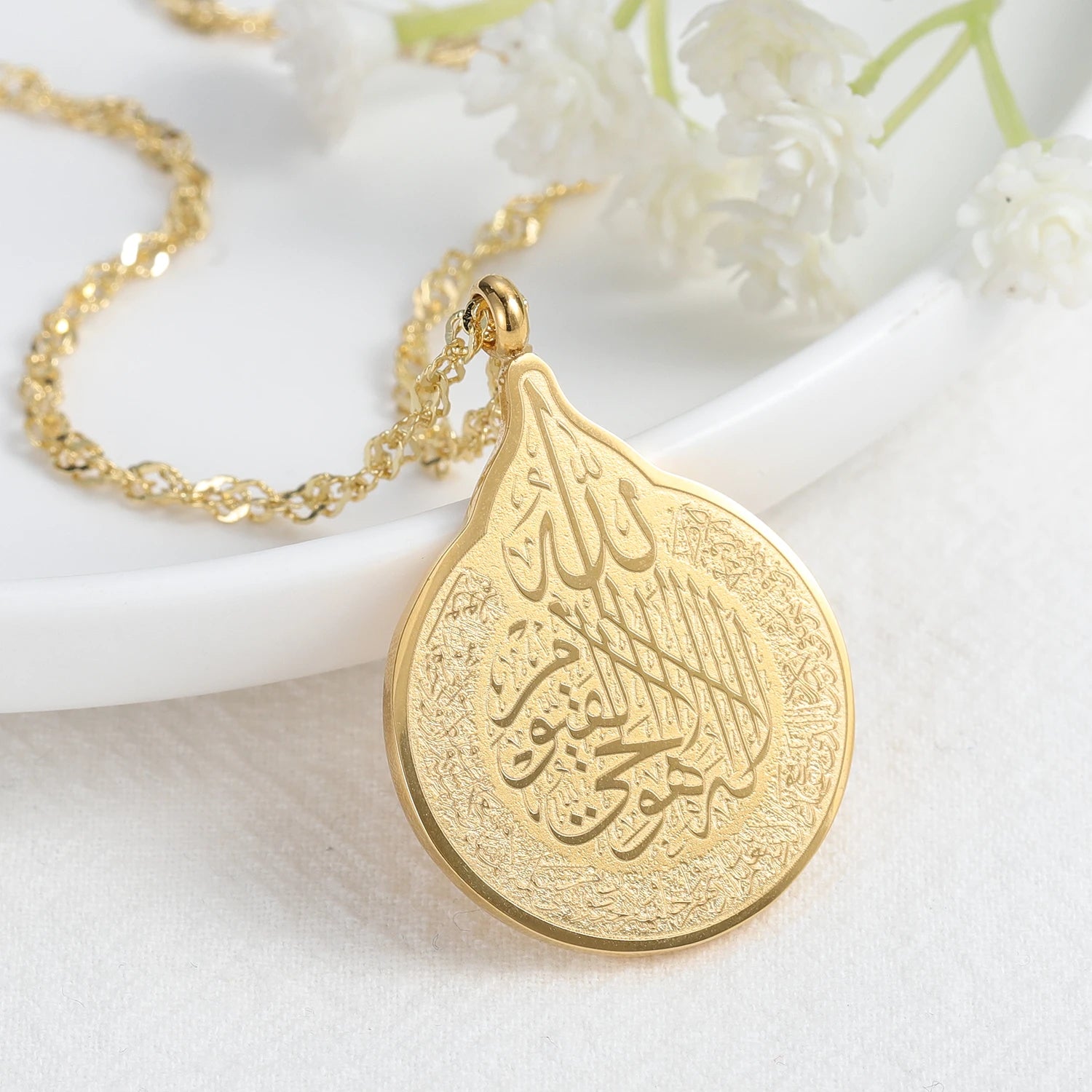 Gold necklace with a teardrop-shaped pendant on a white background