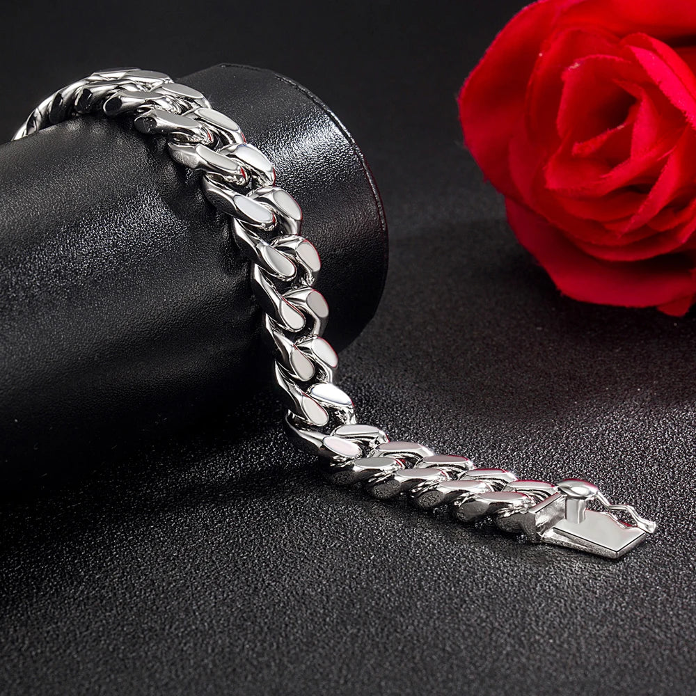 Silver chain bracelet on a black surface with a red rose in the background