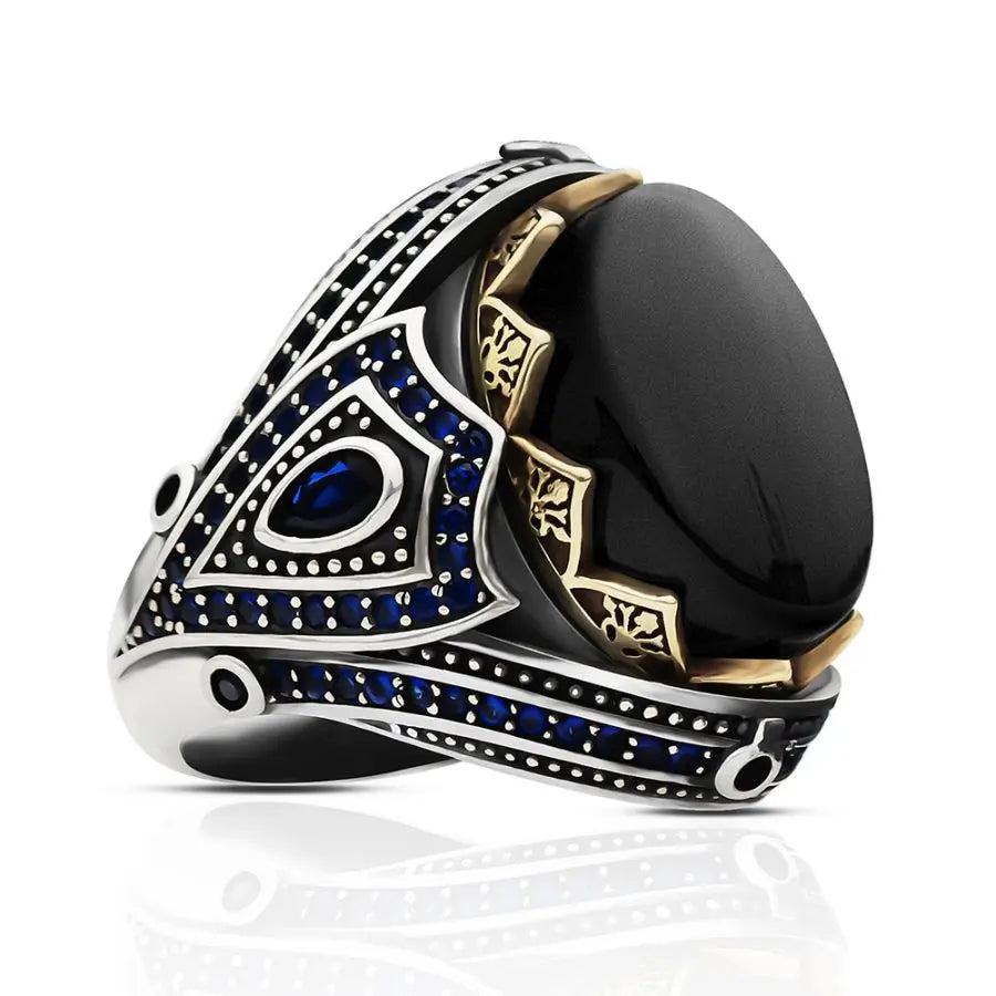 Luxury ring with black stone, gold accents, and blue gemstones on a white background