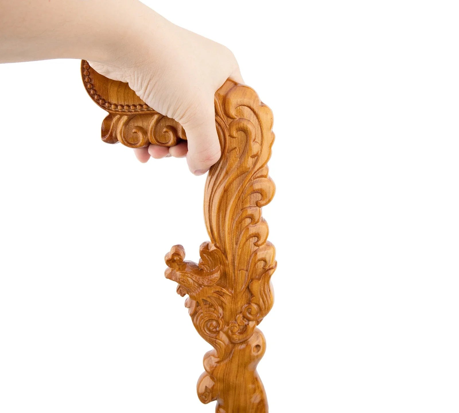 Hand holding a wooden decorative piece with intricate carvings on a white background, featuring the brand 