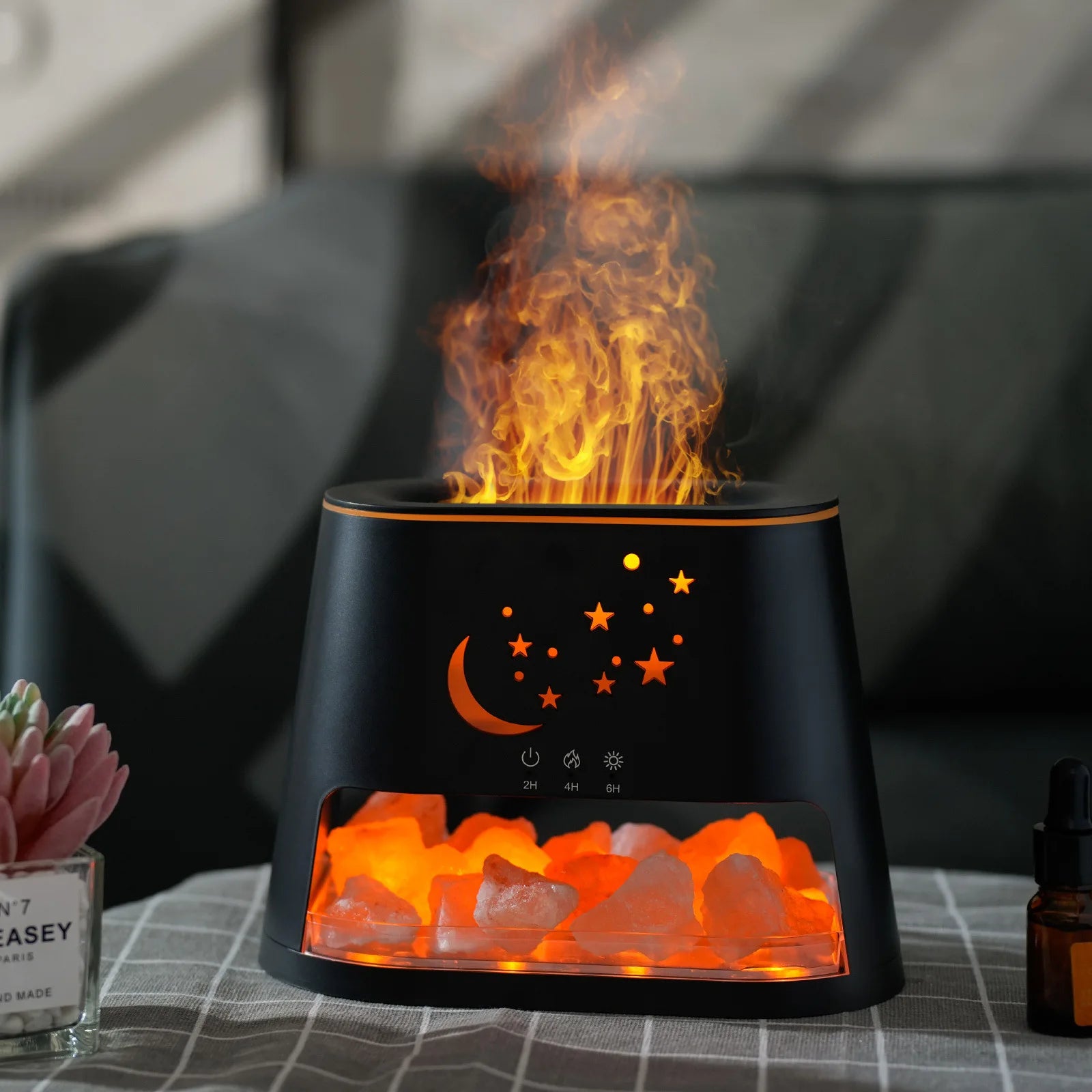 Black lamp with flame effect on a table, featuring celestial designs.