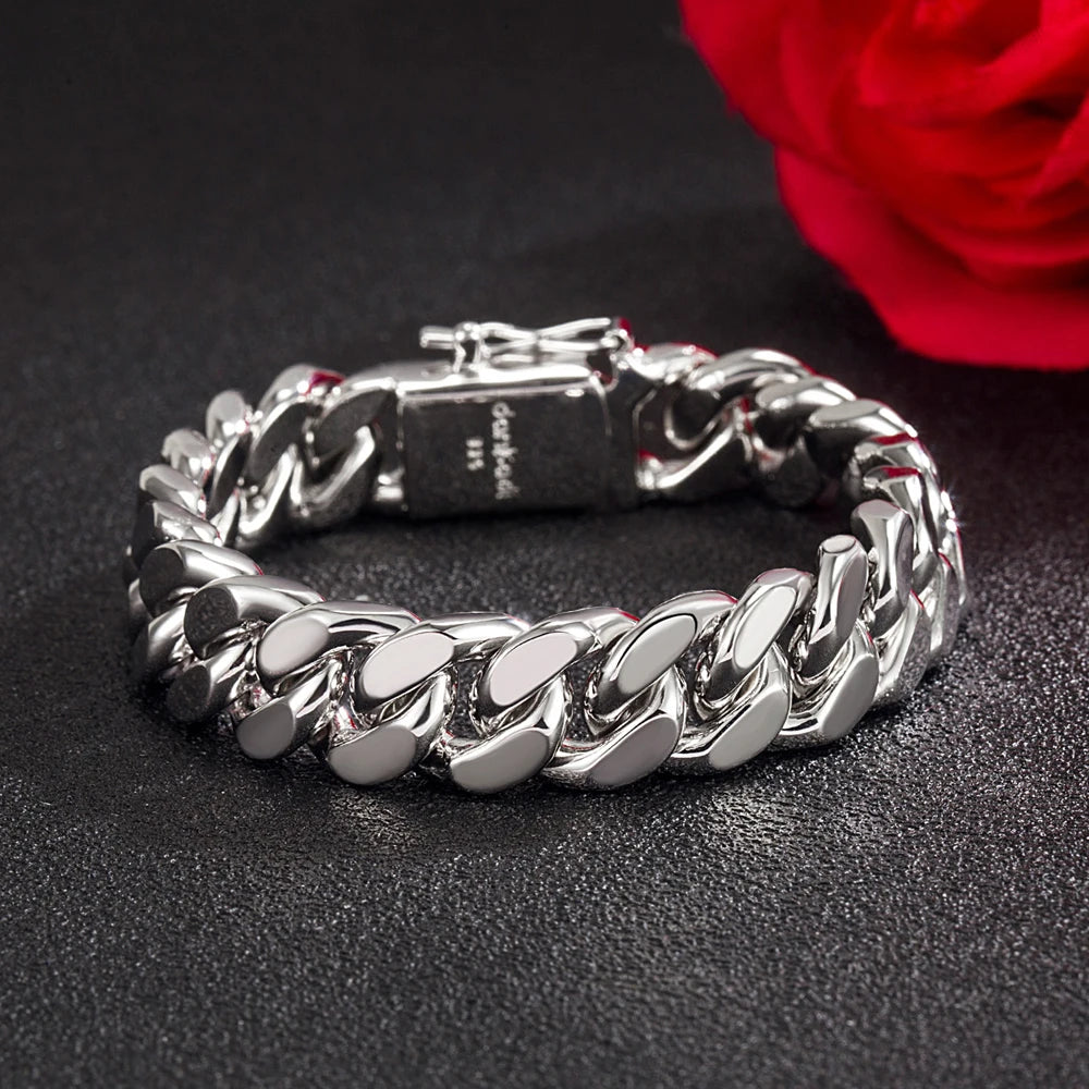 Silver chain bracelet on a dark surface with a red rose in the background