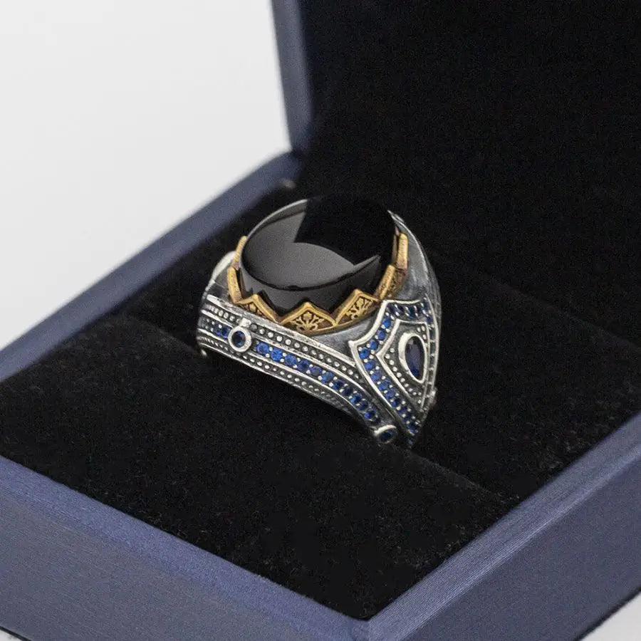 Decorative ring with black stone and blue gemstones in a box