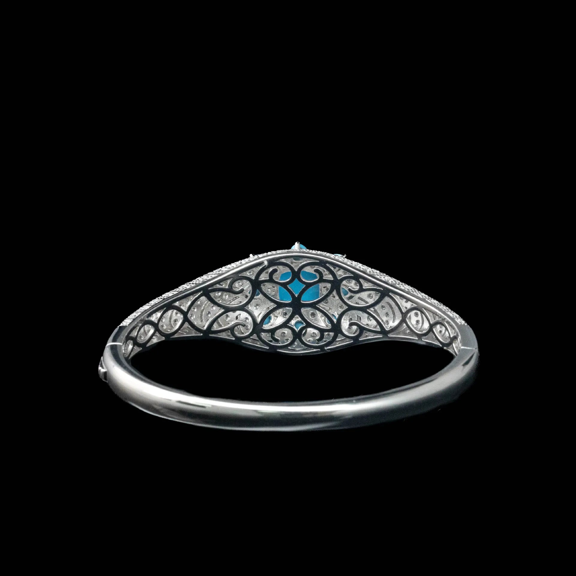 Silver ring with intricate design and blue gemstone on a black background